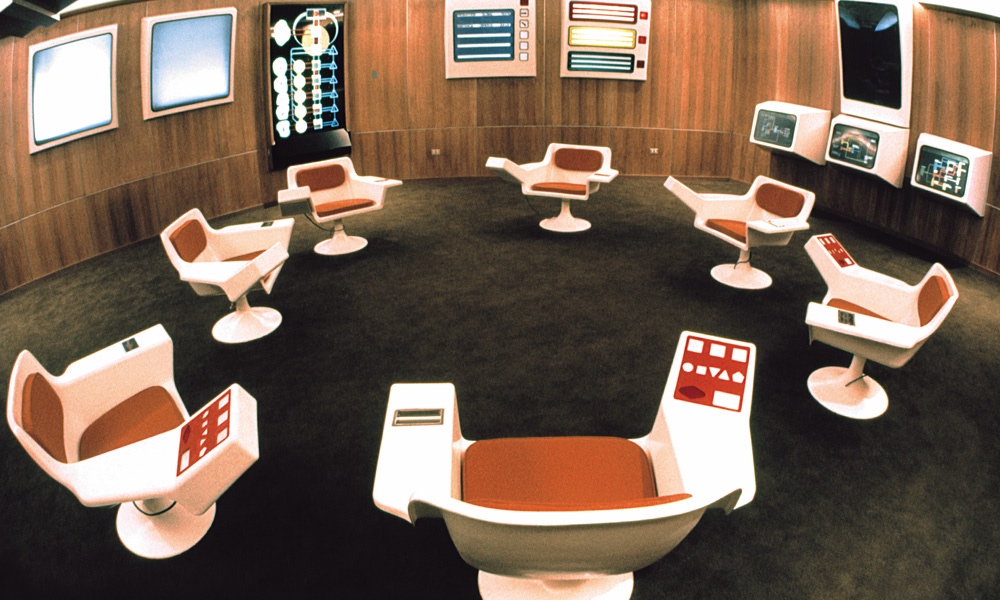 The Cybersyn operations room in Santiago, Chile, circa 1972 — molded fiberglass chairs arranged in a circle facing wall-mounted data screens and control panels
